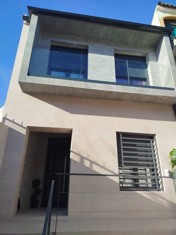 reforma fachada con ventanas y puerta de PVC e instalación de baranda de cristal
